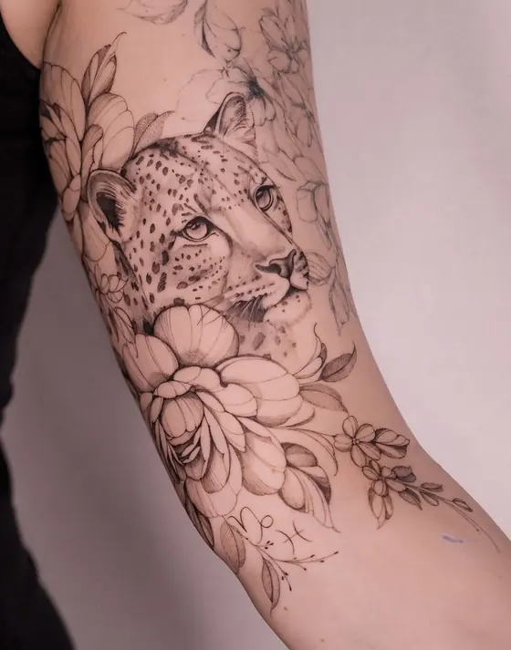 Fine line leopard and floral tattoo on the upper arm by Ingrid Campelo