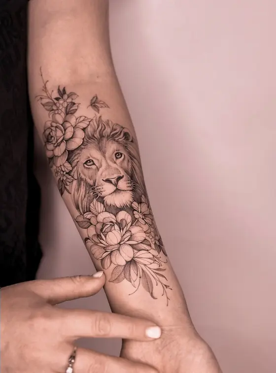 Fine line lion and floral tattoo on the forearm by Ingrid Campelo